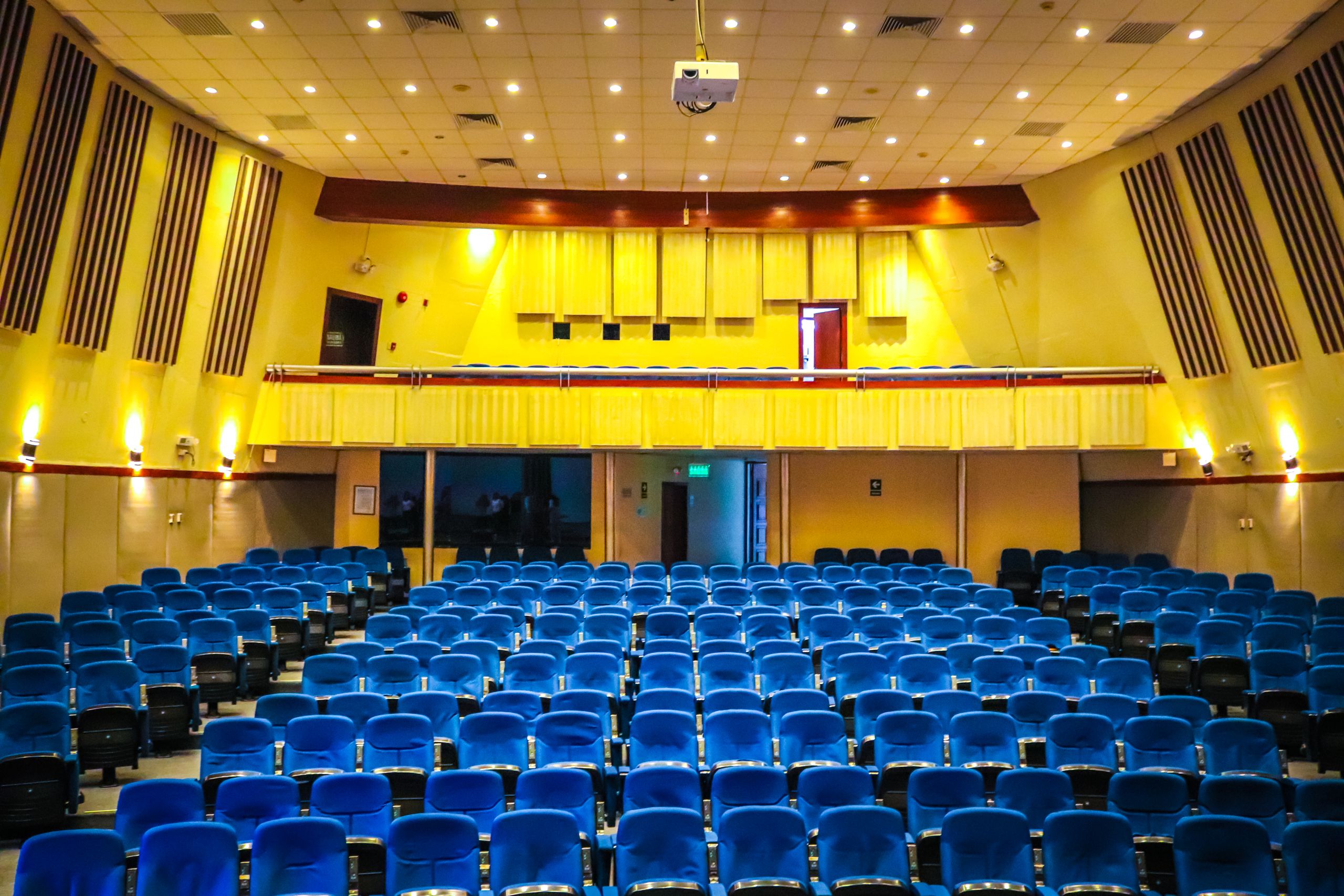Wide-angle view of a vibrant auditorium with blue seats and yellow walls, perfect for events.